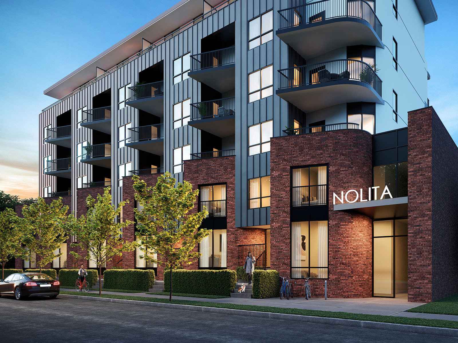 Dusk architectural render of Nolita in Kelowna showing the brick fa&ccedil;ade, dark metal cladding, curved balconies and illuminated entrance.