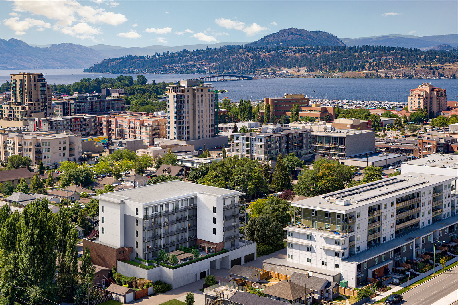 Aerial CGI composite of Nolita in downtown Kelowna with Okanagan Lake, the William R. Bennett Bridge and surrounding mountains.
